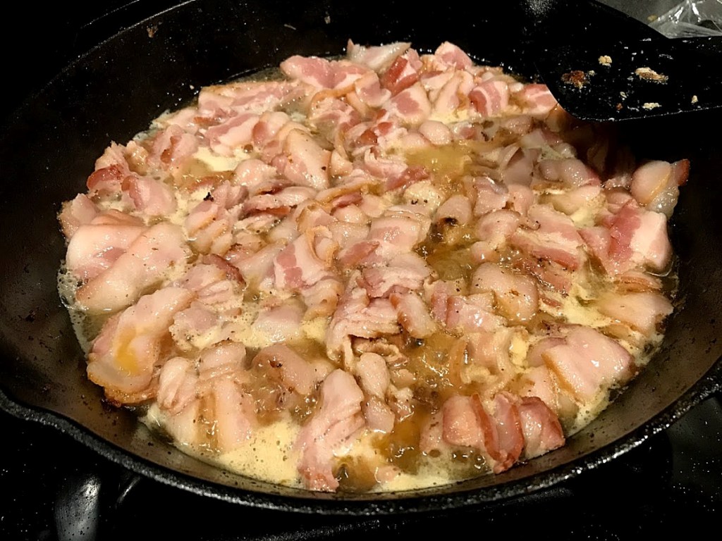Raw bacon being cooked in water to prevent shrinkage and splattering.